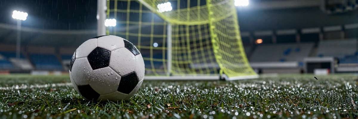 Fu&szlig;ball auf regennassem Spielfeld unter Stadionflutlicht mit lime-gr&uuml;nem Tornetz im Hintergrund bei Golisimo Sportwetten